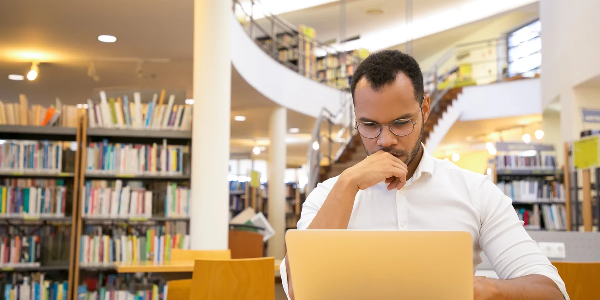 Professional analyzing information on a laptop in a library