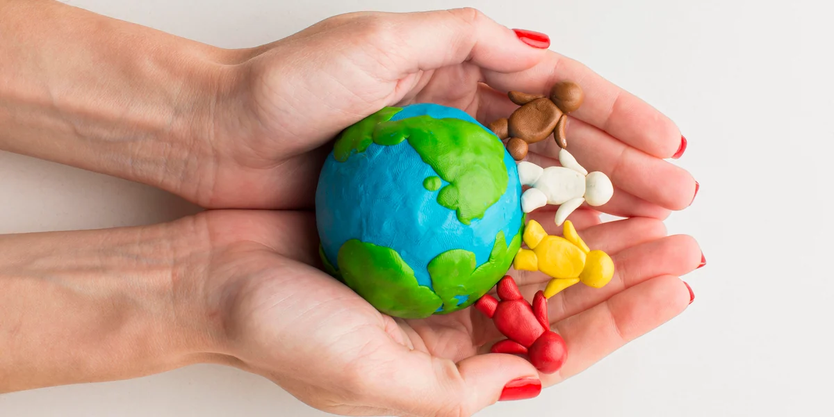 Hands protecting a planet and human figures made of colored dough