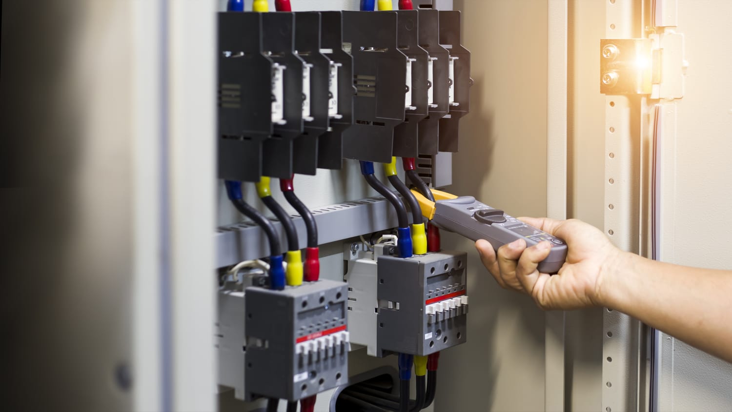 Technician inspecting components of an electrical distribution panel