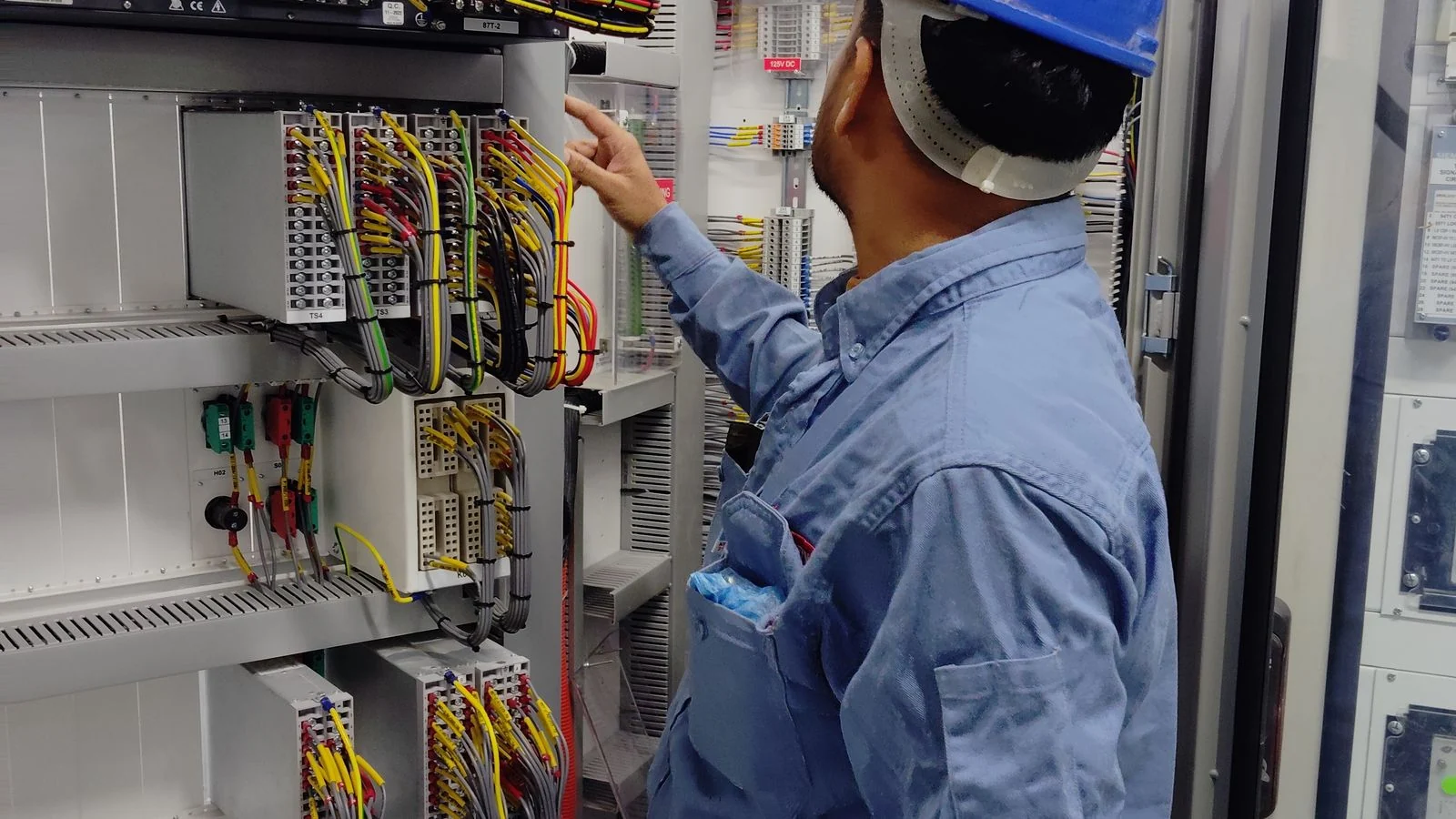 Técnico inspeciona componentes de um quadro elétrico industrial